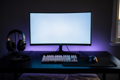 Setup PC gaming avec écran incurvé, clavier mécanique et casque, ambiance soirée et lumière RGB feutrée