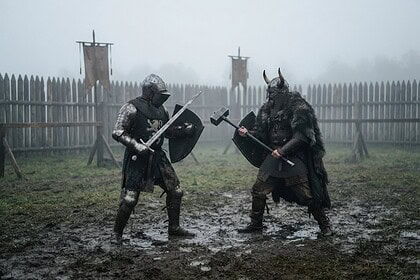 Deux combattants en armure médiévale face à face dans une arène boueuse et brumeuse, épée et masse levées