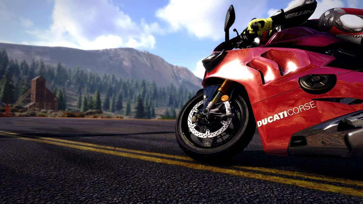 Moto Ducati rouge vue au ras du bitume sur une route de montagne ensoleillée