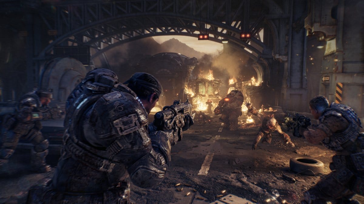 Capture de Gears of War: E-Day : des soldats en armure affrontent des créatures sous un pont métallique en flammes