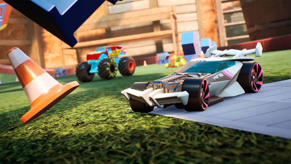 Bolide blanc futuriste et monster truck bleu sur une pelouse d'arrière-cour, près d'un cône de chantier