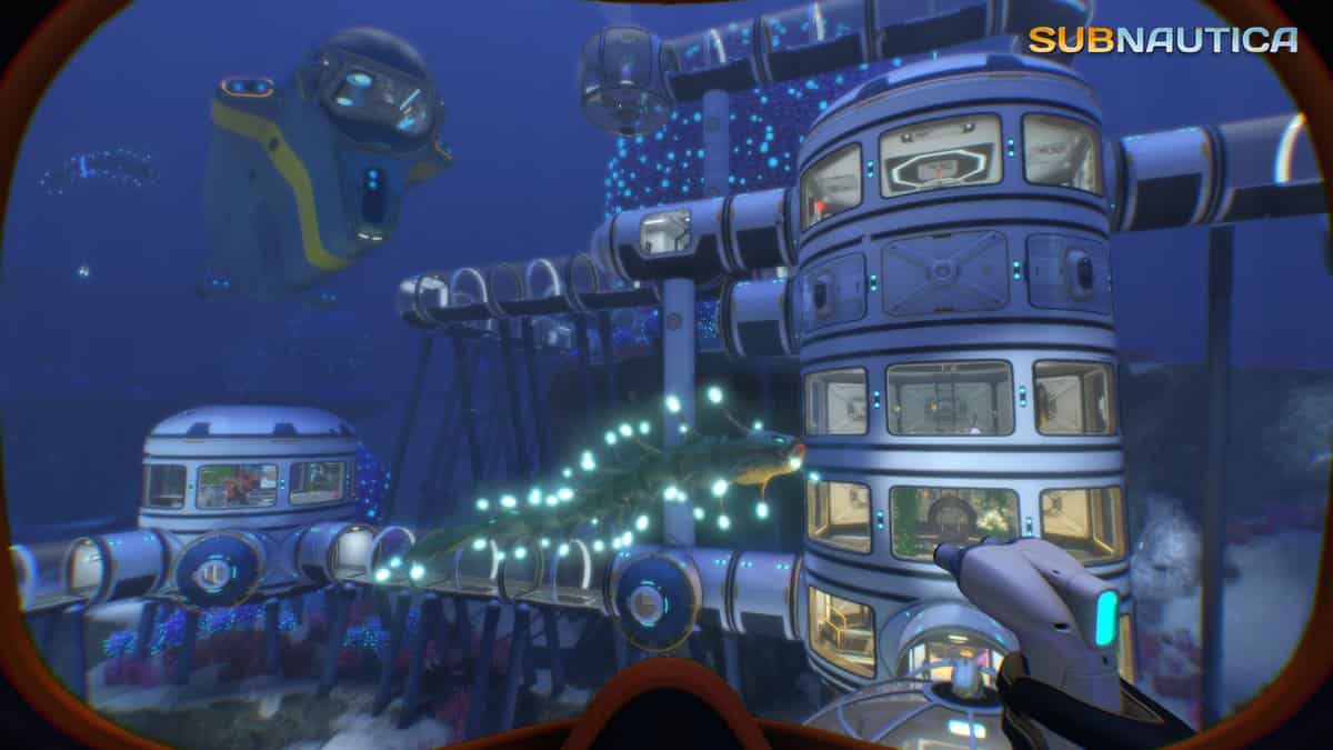 Base sous-marine faite de modules cylindriques éclairés, reliés par des couloirs vitrés, entourée de poissons